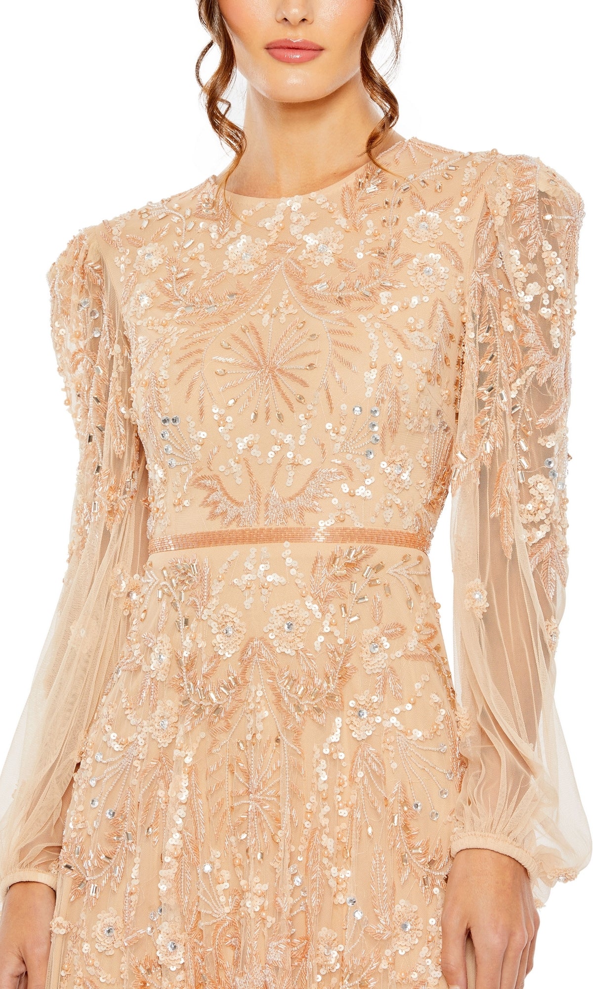 A woman wears the Mac Duggal 93930 Long Sleeve Beaded Formal Gown, a sheer nude evening dress adorned with sparkling sequin and bead accents in floral and geometric designs.